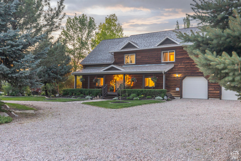 View of front facade featuring a porch, driveway, a garage, and roof with shingles