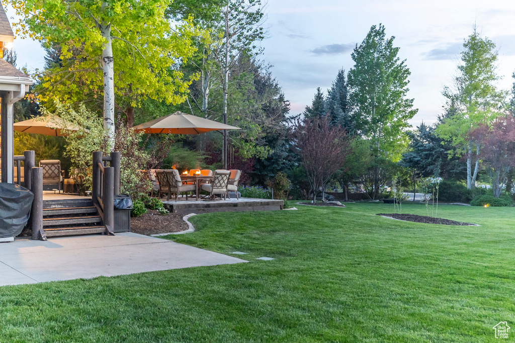 View of grassy yard featuring a patio area
