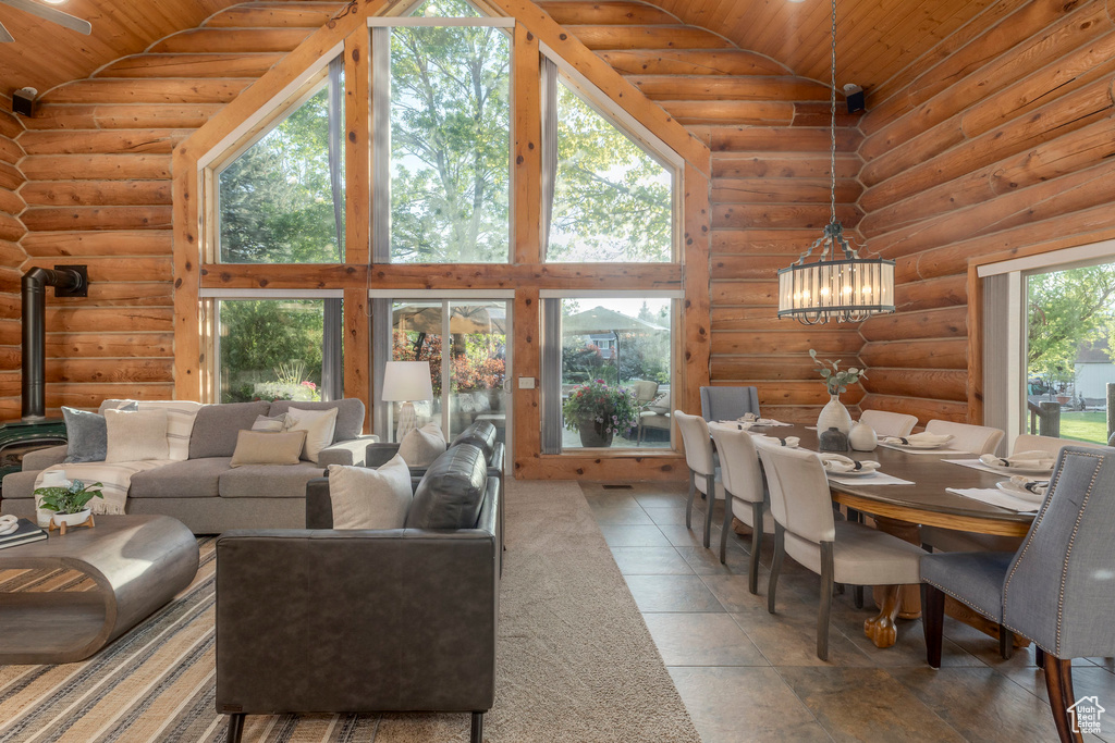 Living room with high vaulted ceiling, wooden ceiling, rustic walls, a wood stove, and a chandelier