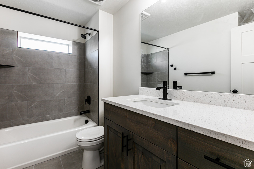 Full bathroom featuring tile patterned flooring, toilet, vanity, and tiled shower / bath