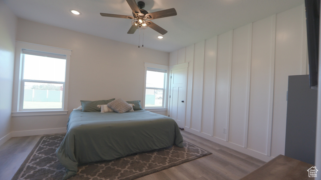 Bedroom featuring ceiling fan, multiple windows, and hardwood / wood-style floors