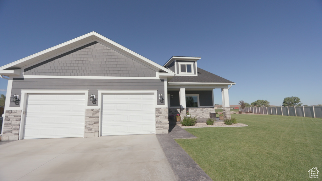 Craftsman inspired home featuring a garage and a front lawn