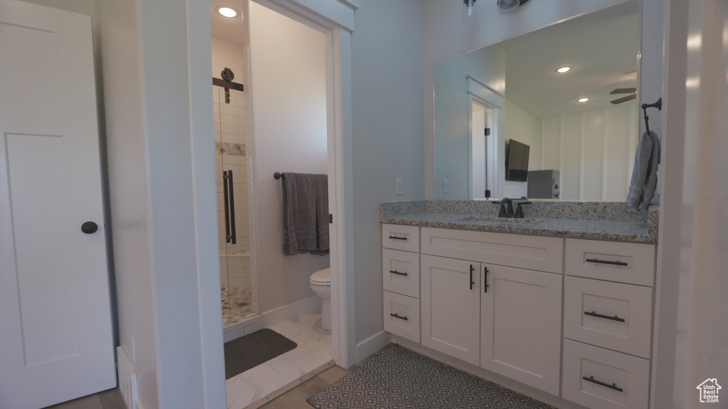 Bathroom featuring tiled shower, tile flooring, vanity, and toilet