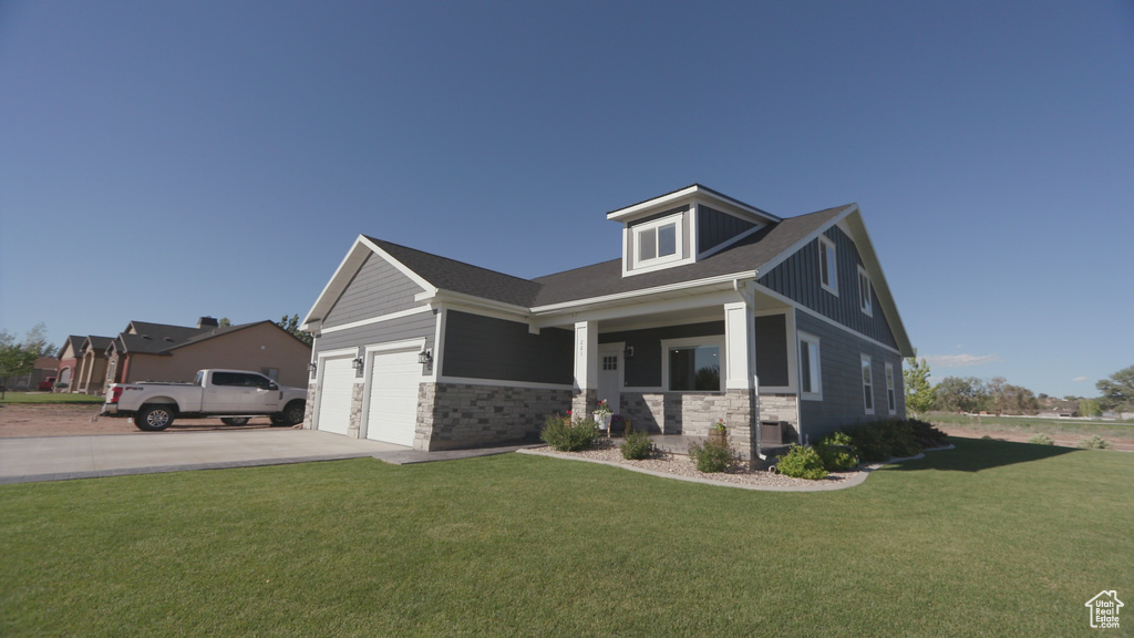 View of front of house with a garage, a front yard, and covered porch