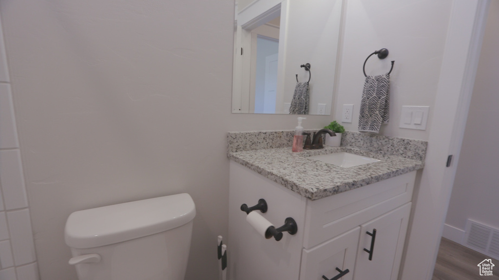 Bathroom with hardwood / wood-style floors, toilet, and vanity