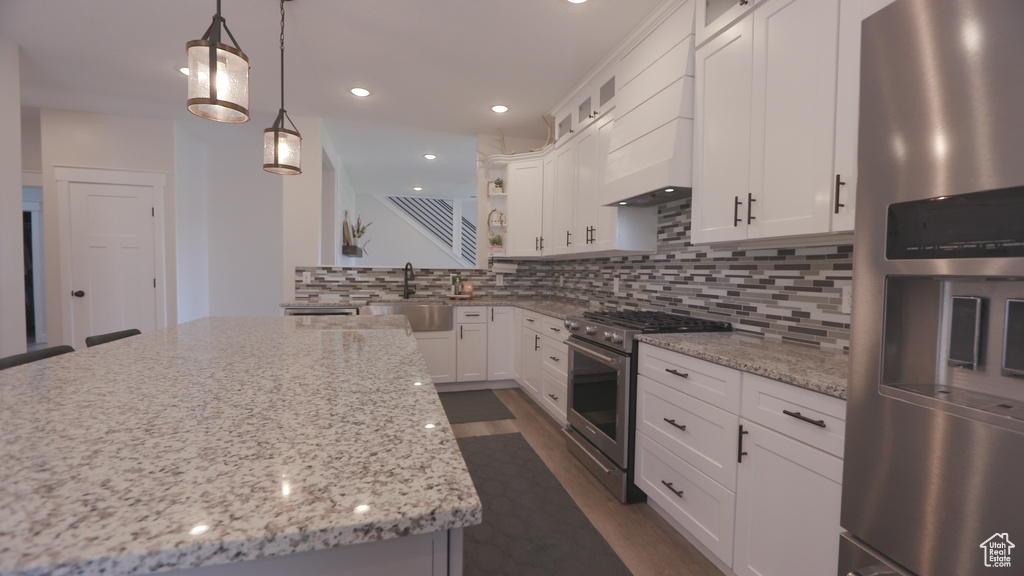 Kitchen featuring stainless steel appliances, sink, white cabinetry, and backsplash