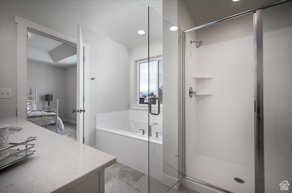 Bathroom with vanity, tile flooring, plus walk in shower, and a textured ceiling