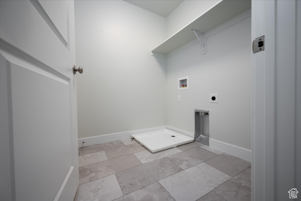 Laundry room with hookup for a washing machine, electric dryer hookup, and light tile floors