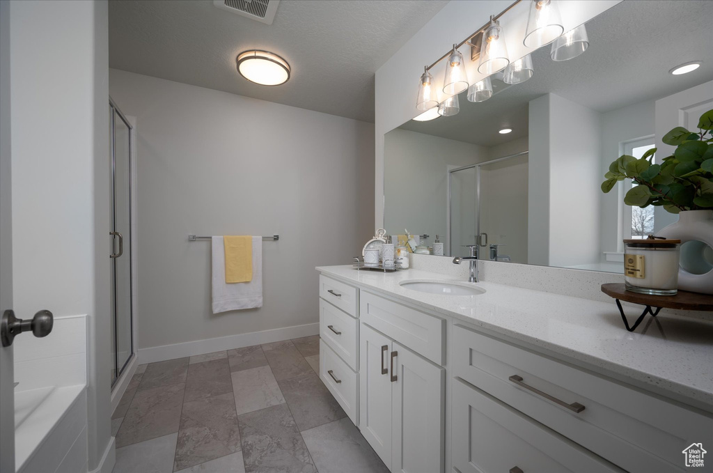 Bathroom featuring tile floors, plus walk in shower, and vanity