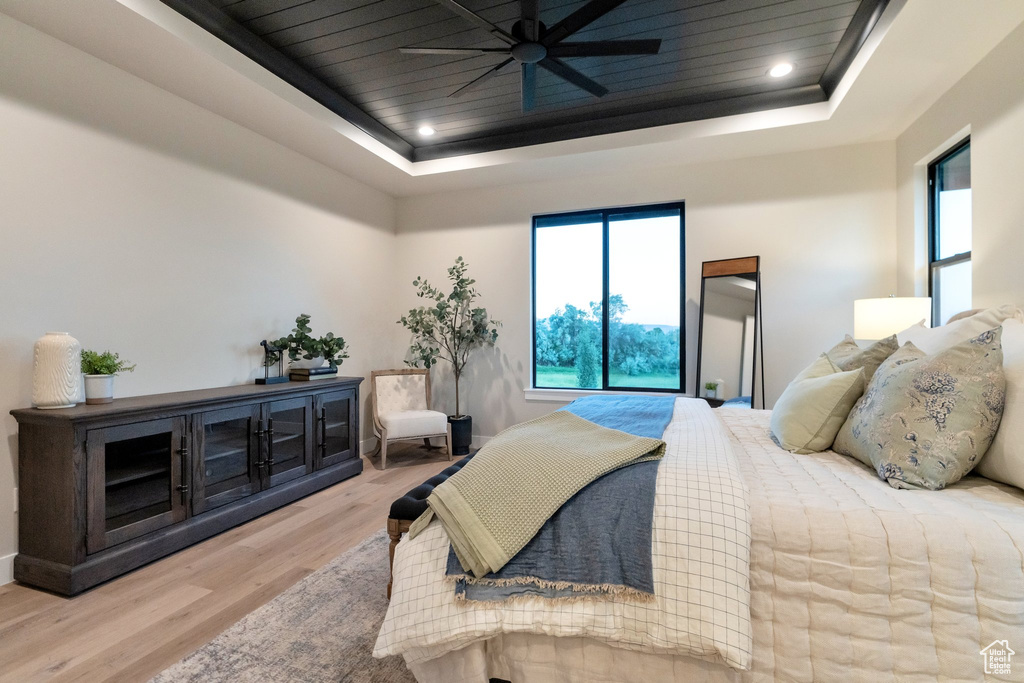 Bedroom featuring wood-type flooring, ceiling fan, and a tray ceiling