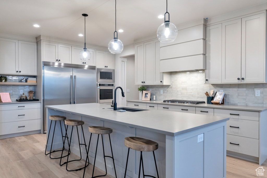 Kitchen with built in appliances, backsplash, and light wood-type flooring