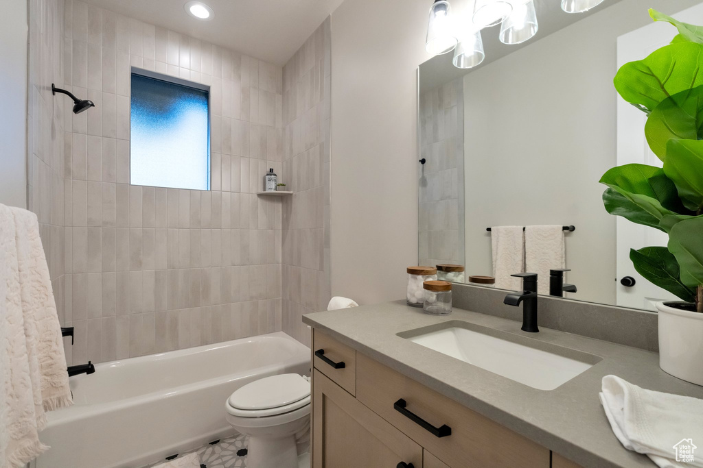 Full bathroom with tiled shower / bath, toilet, and vanity with extensive cabinet space