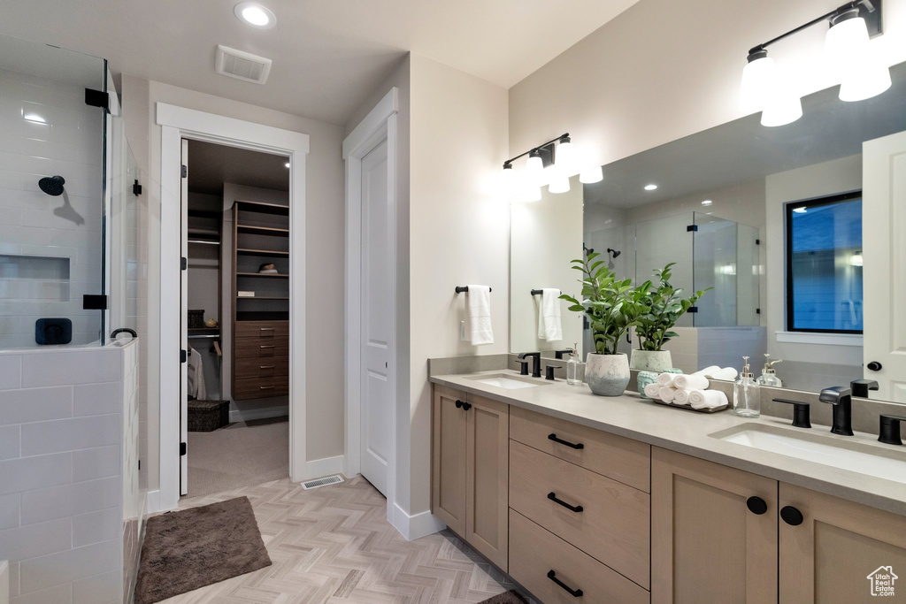 Bathroom with dual vanity, a shower with door, and parquet flooring