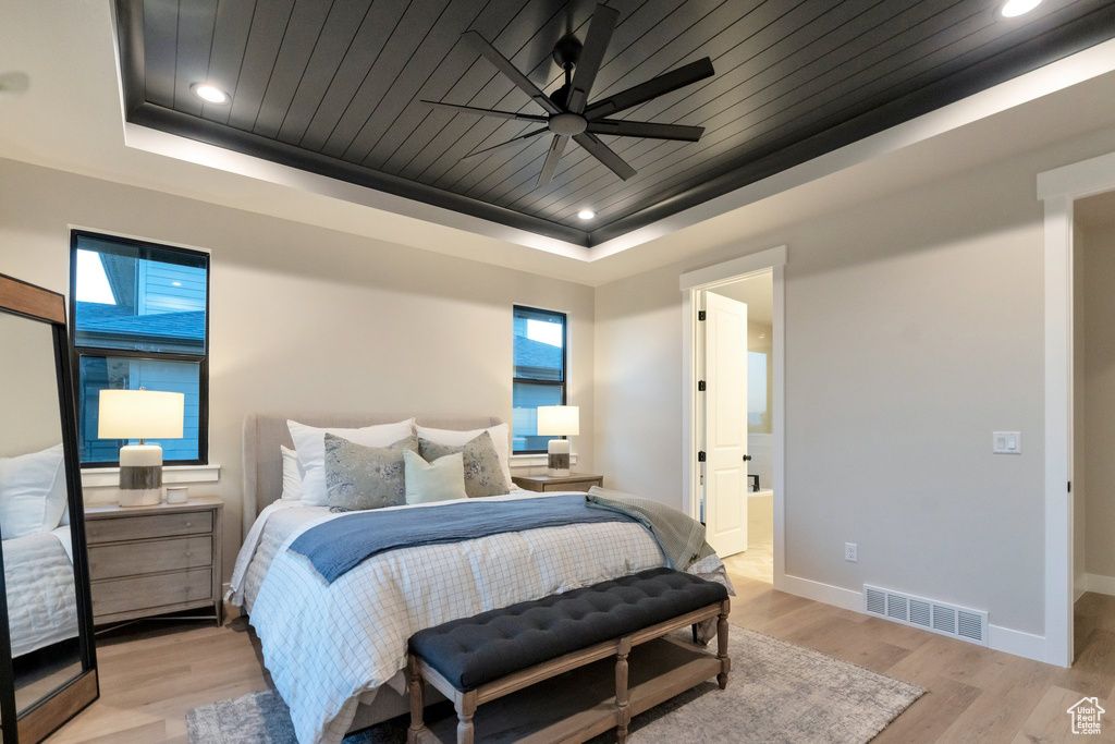 Bedroom featuring ceiling fan, a tray ceiling, and light wood-type flooring