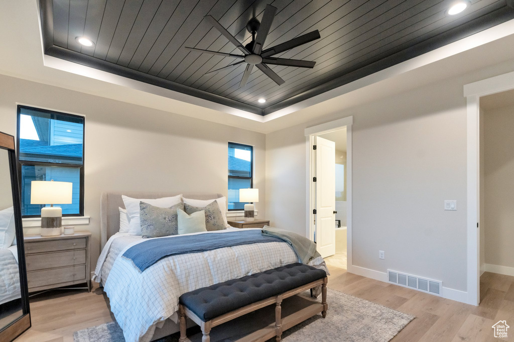 Bedroom featuring ceiling fan, a raised ceiling, and light hardwood / wood-style flooring