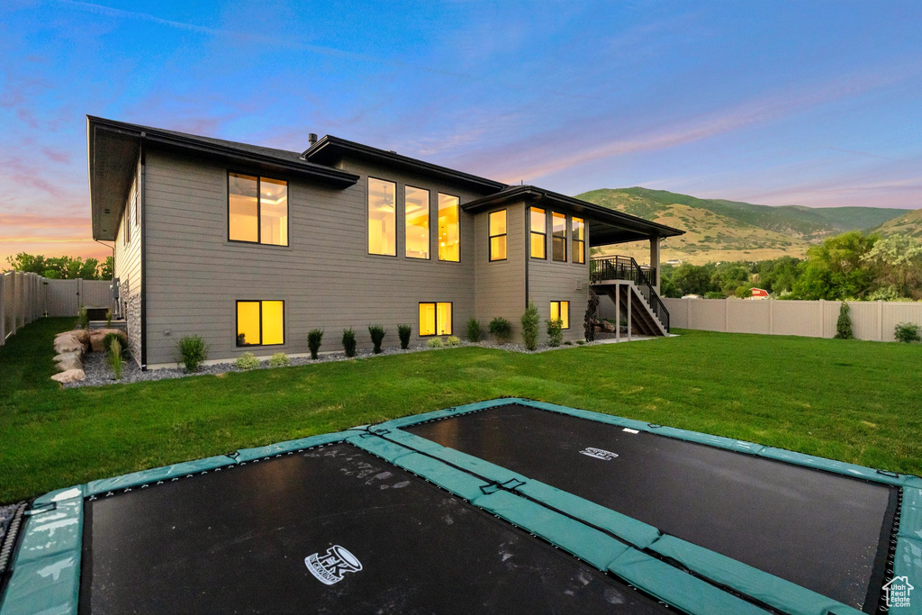 Back house at dusk featuring a yard and a mountain view