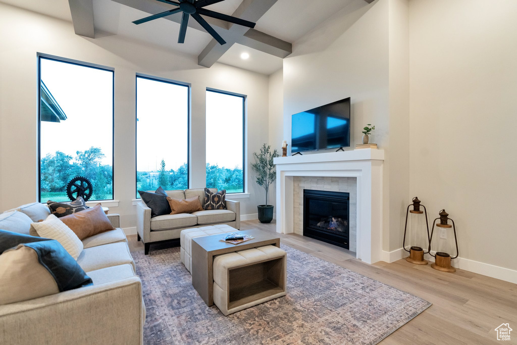 Living room featuring beam ceiling, ceiling fan, hardwood / wood-style flooring, and a fireplace