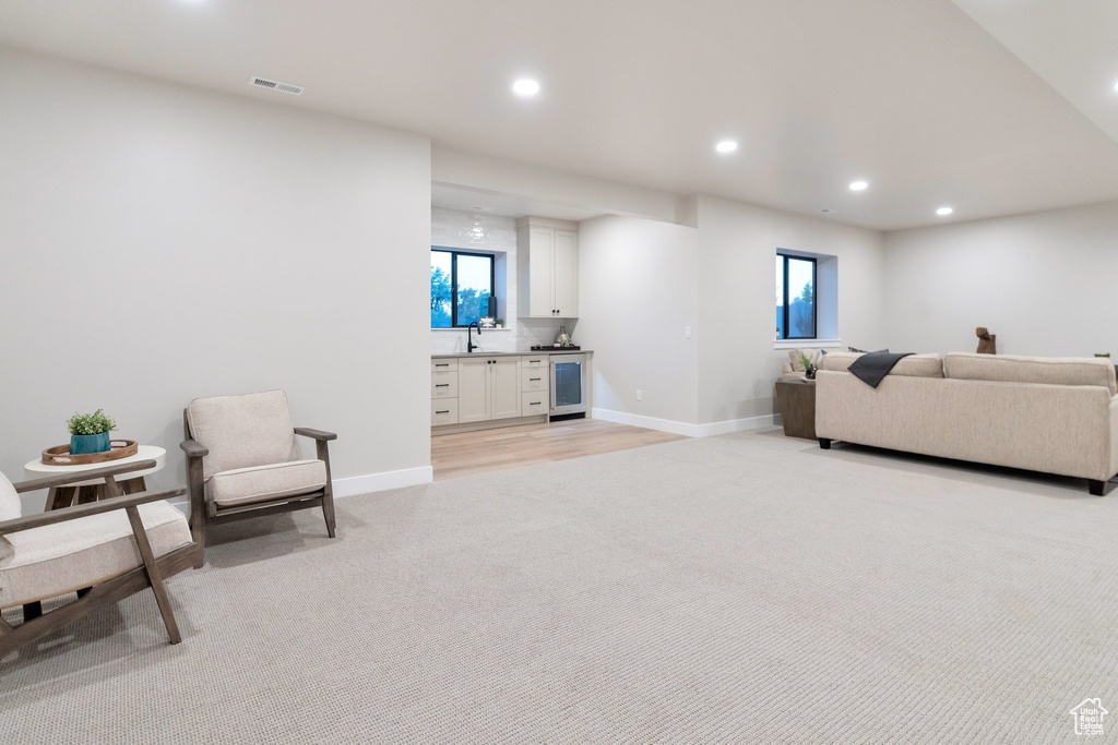 Carpeted living room with beverage cooler and sink