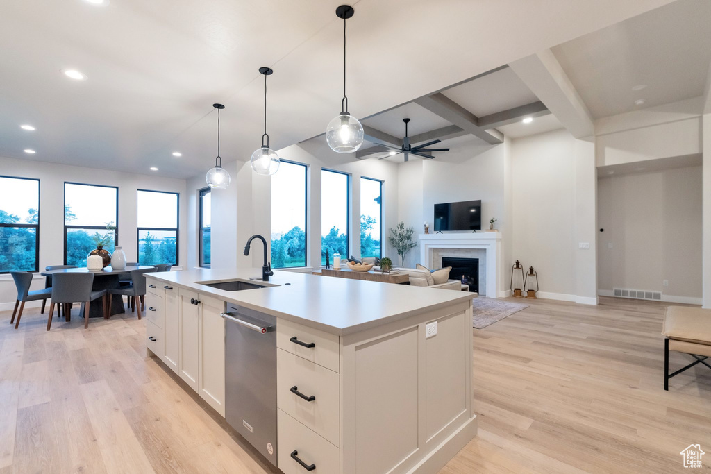 Kitchen with coffered ceiling, an island with sink, light wood-type flooring, sink, and pendant lighting