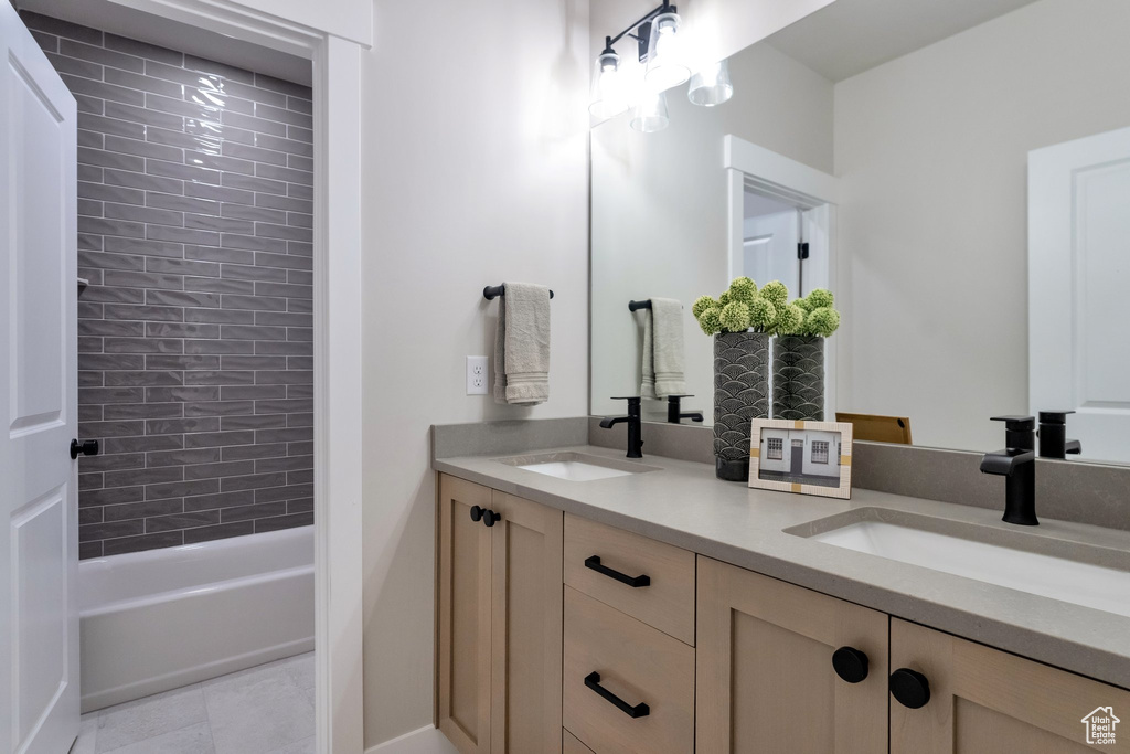 Bathroom with tile flooring, dual vanity, and tiled shower / bath