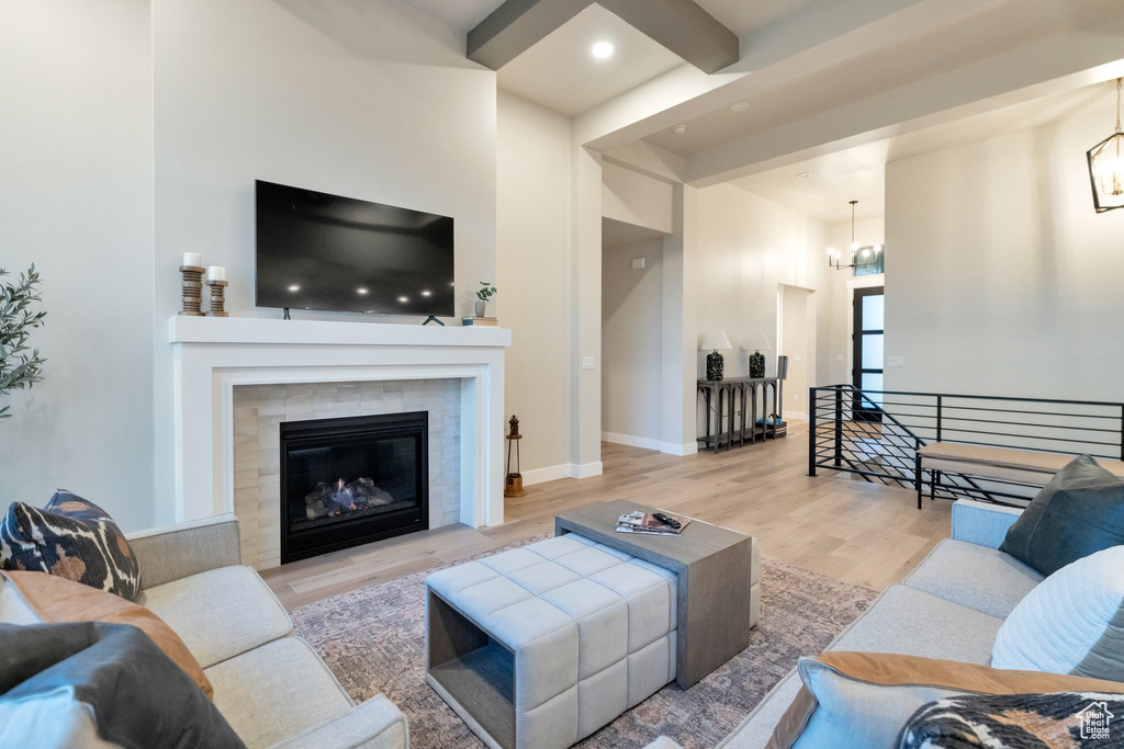 Living room with a fireplace, a towering ceiling, beamed ceiling, hardwood / wood-style flooring, and a chandelier