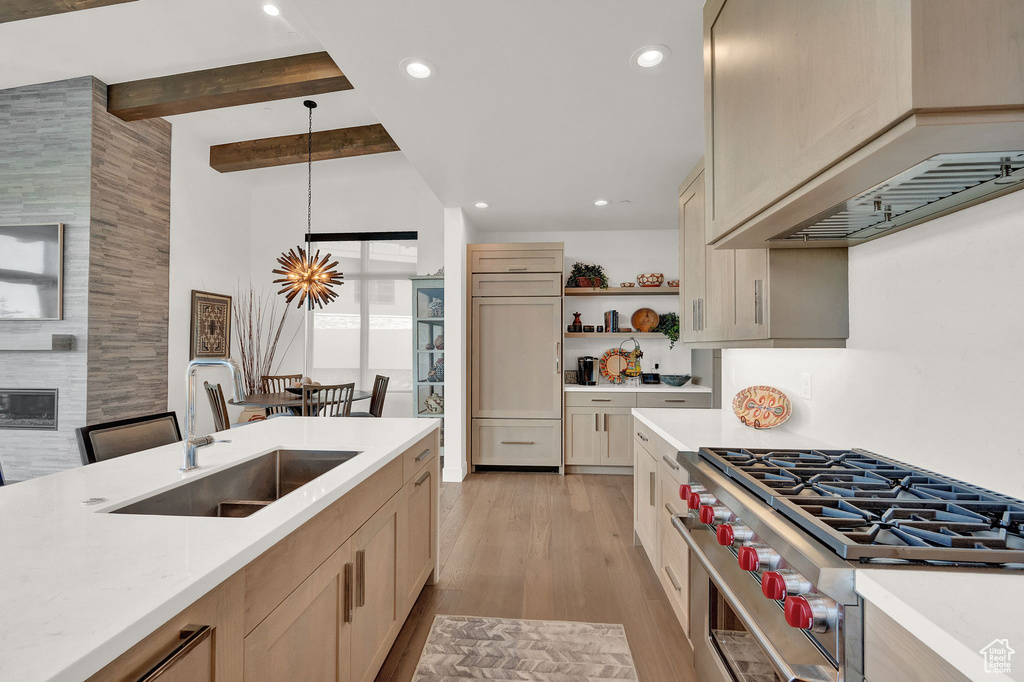 Kitchen with light brown cabinets, designer range, custom exhaust hood, light wood-type flooring, and pendant lighting