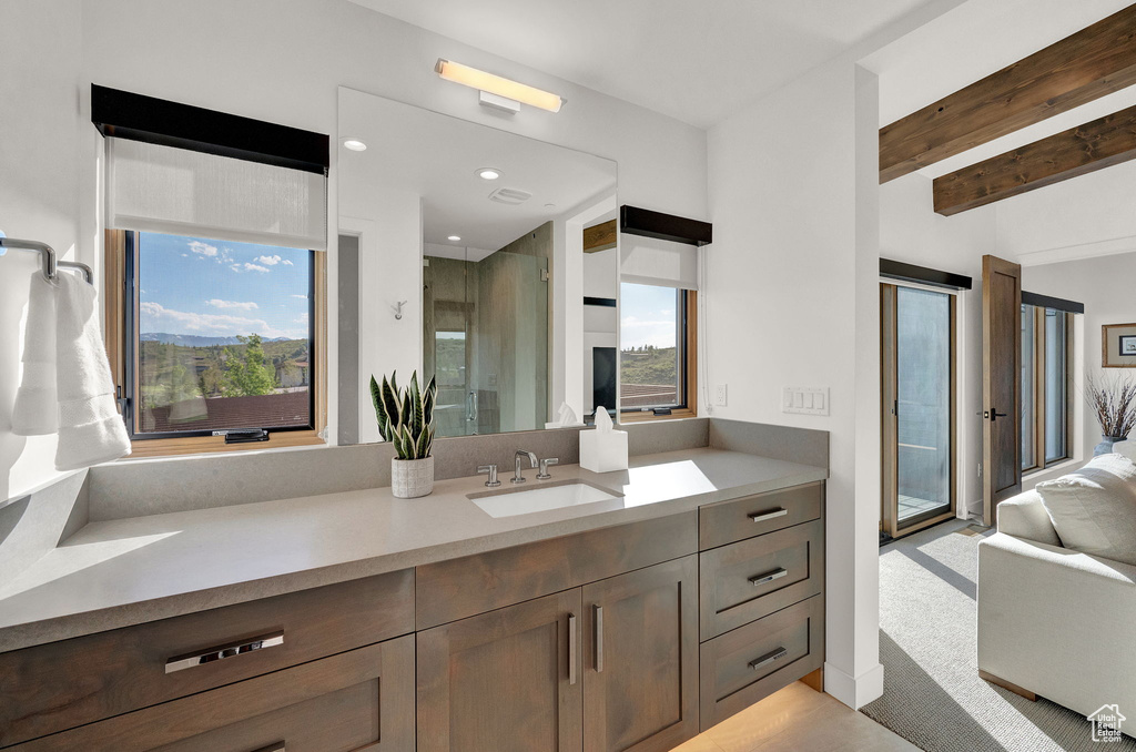 Bathroom with walk in shower, beam ceiling, a wealth of natural light, and vanity