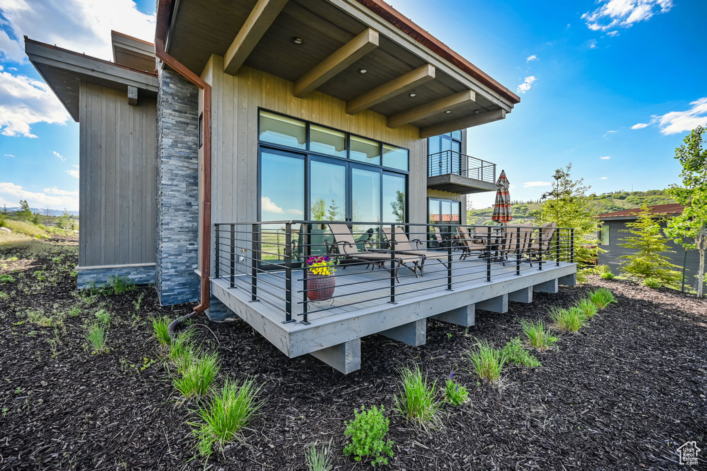 View of side of property featuring a wooden deck and a balcony