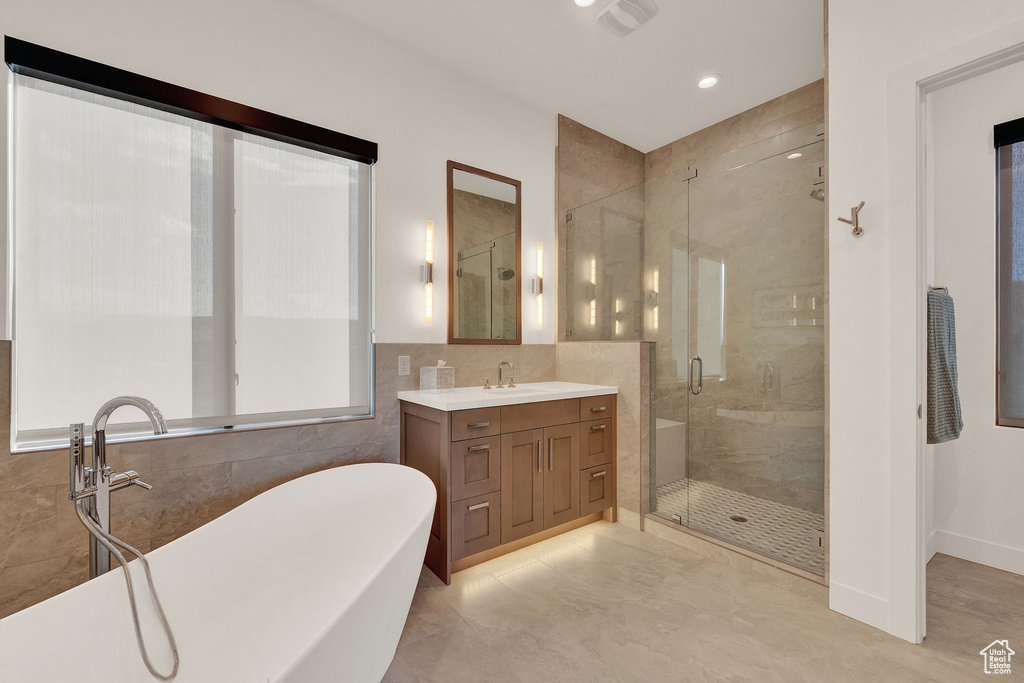 Bathroom featuring tile walls, tile floors, plus walk in shower, and oversized vanity