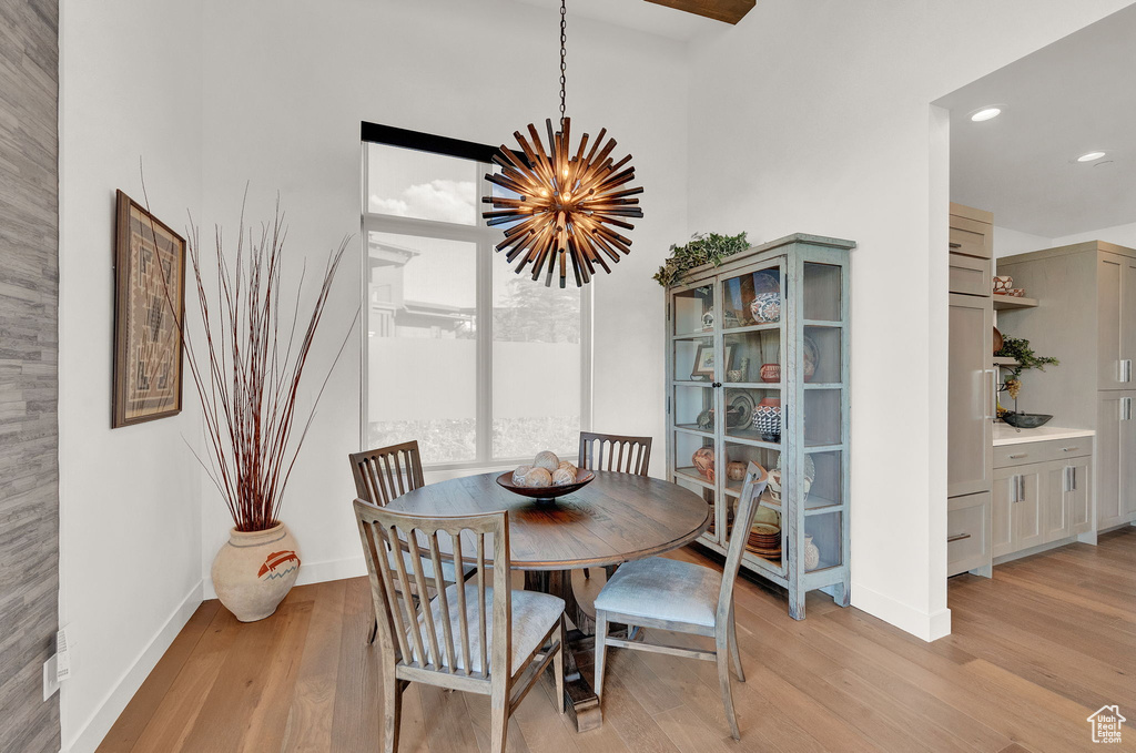 Dining room with a high ceiling, a notable chandelier, and light hardwood / wood-style flooring