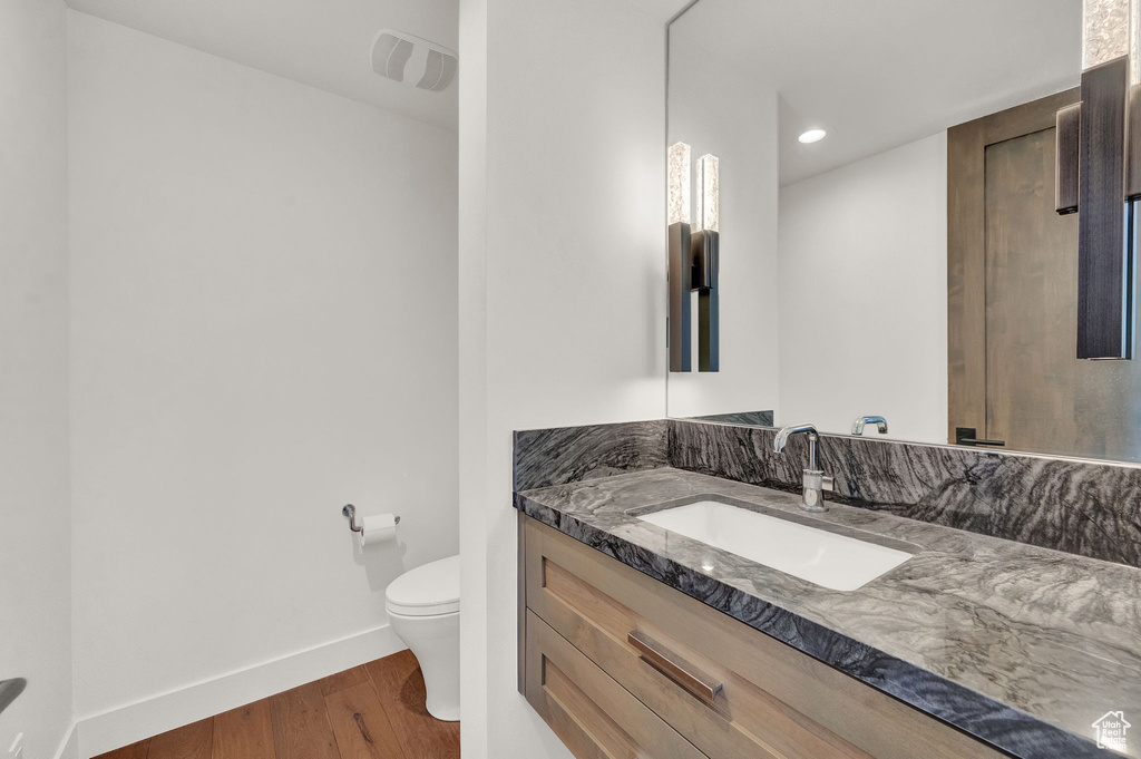 Bathroom featuring wood-type flooring, oversized vanity, and toilet