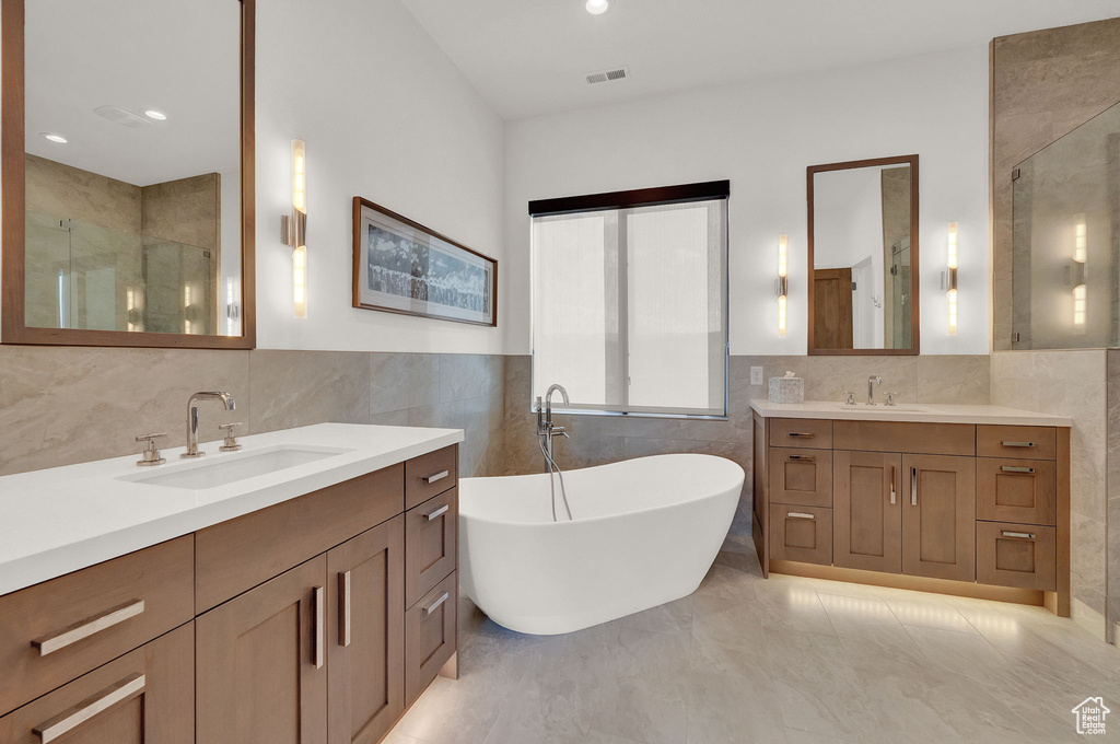 Bathroom featuring backsplash, tile flooring, tile walls, and double vanity