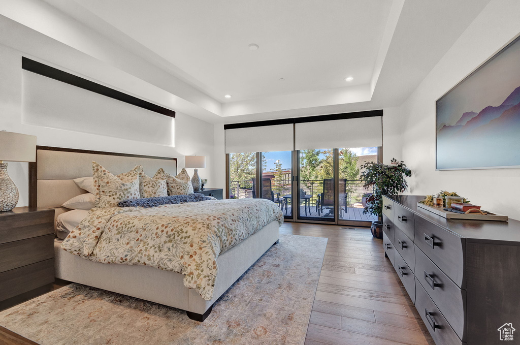 Bedroom featuring a raised ceiling, access to exterior, and dark hardwood / wood-style flooring