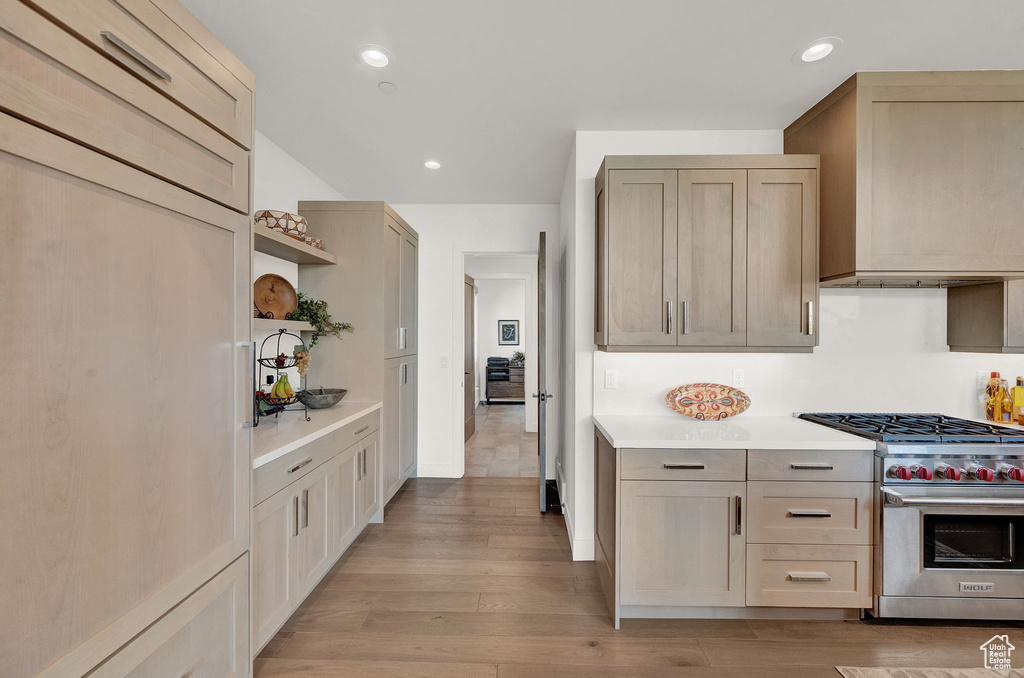 Kitchen with custom range hood, light hardwood / wood-style floors, and premium range