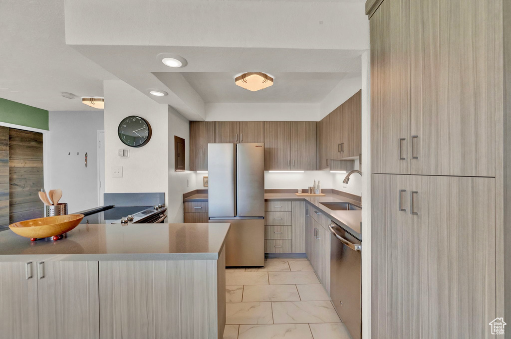 Kitchen with light tile patterned floors, stainless steel appliances, sink, and kitchen peninsula