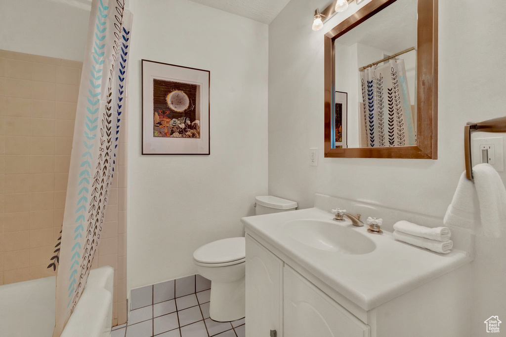 Full bathroom featuring tile patterned flooring, toilet, vanity, and shower / tub combo with curtain