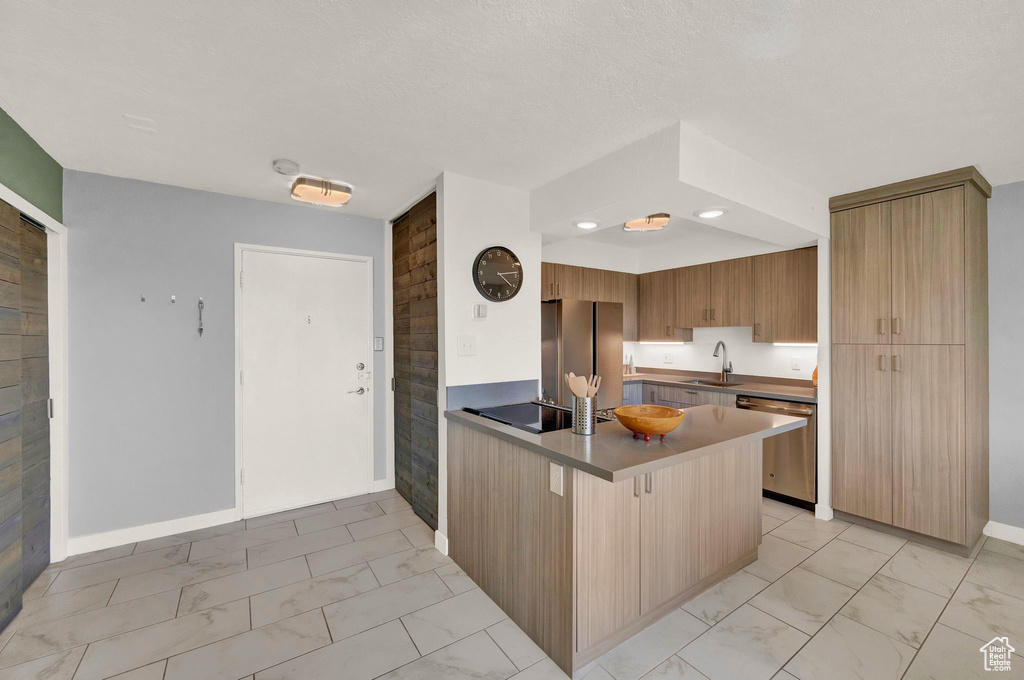 Kitchen featuring light tile patterned floors, stainless steel appliances, sink, and kitchen peninsula