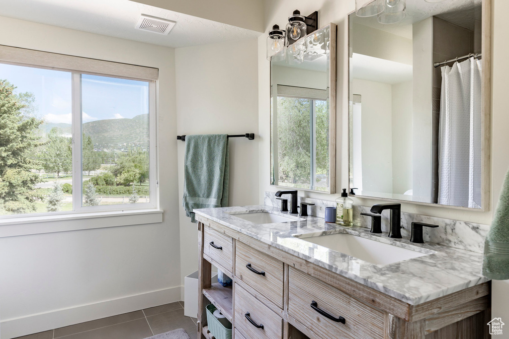 Bathroom featuring tile floors, a wealth of natural light, and double sink vanity