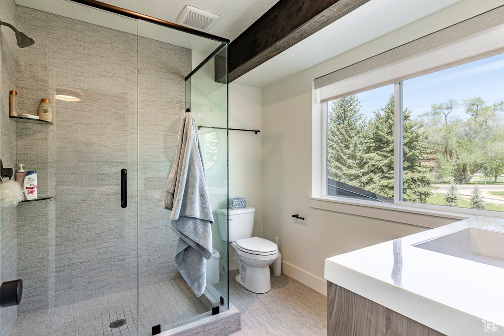 Bathroom featuring a shower with shower door, toilet, and vanity