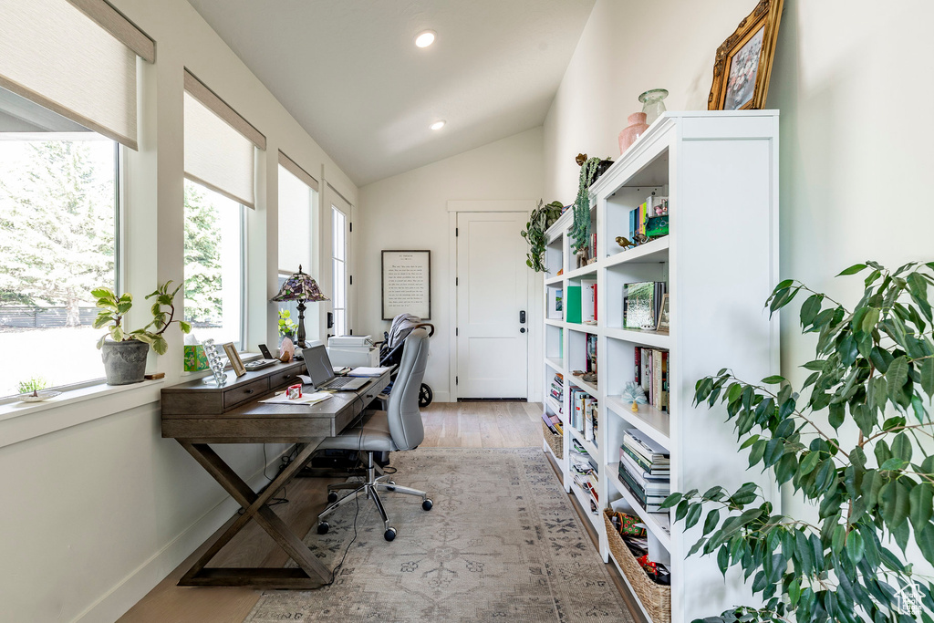 Home office with light hardwood / wood-style floors and vaulted ceiling