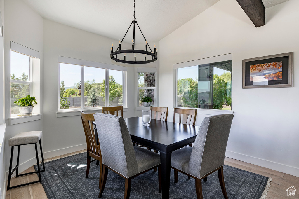 Dining space featuring an inviting chandelier, hardwood / wood-style floors, and lofted ceiling with beams