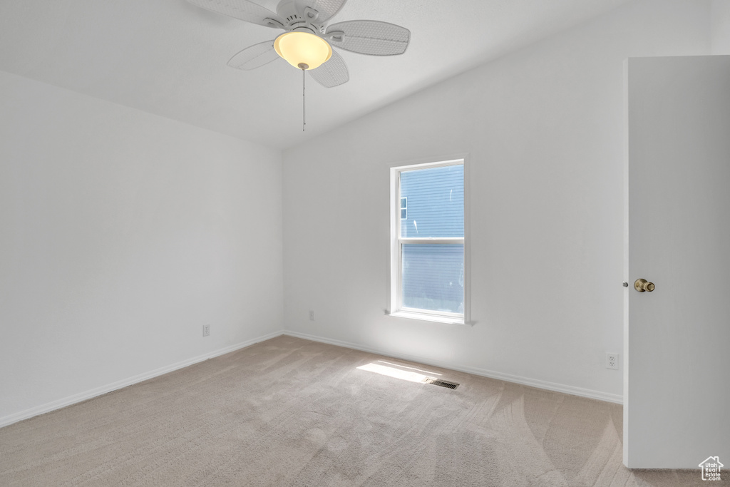 Carpeted spare room featuring lofted ceiling and ceiling fan