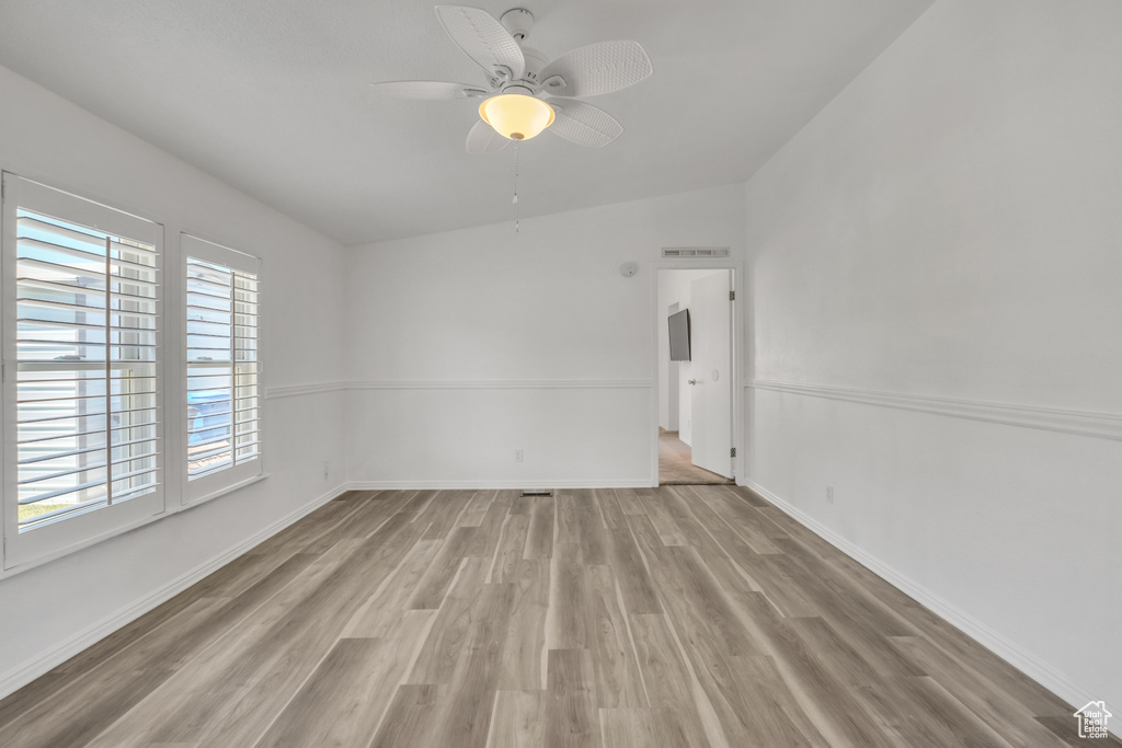 Spare room featuring a wealth of natural light, ceiling fan, vaulted ceiling, and hardwood / wood-style flooring