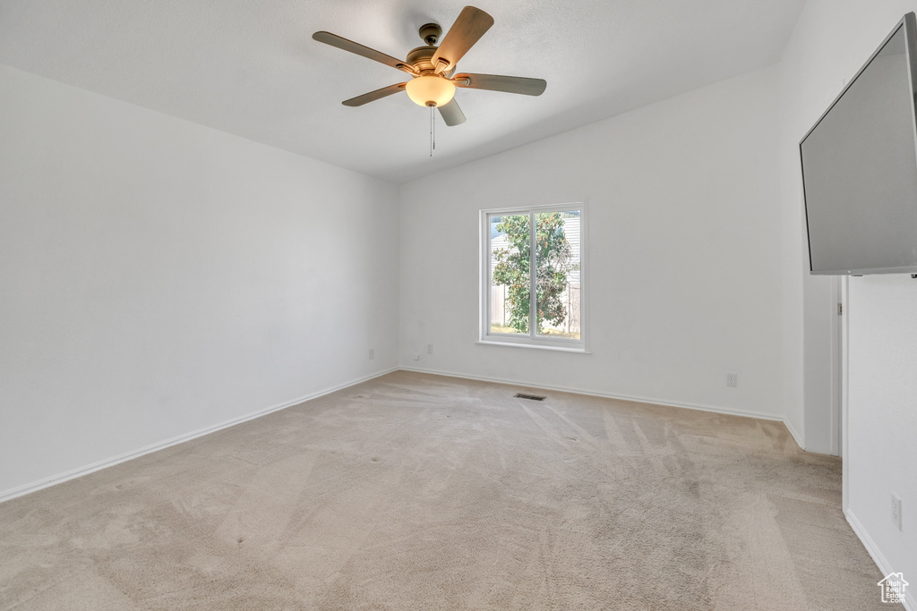 Carpeted empty room featuring ceiling fan and lofted ceiling