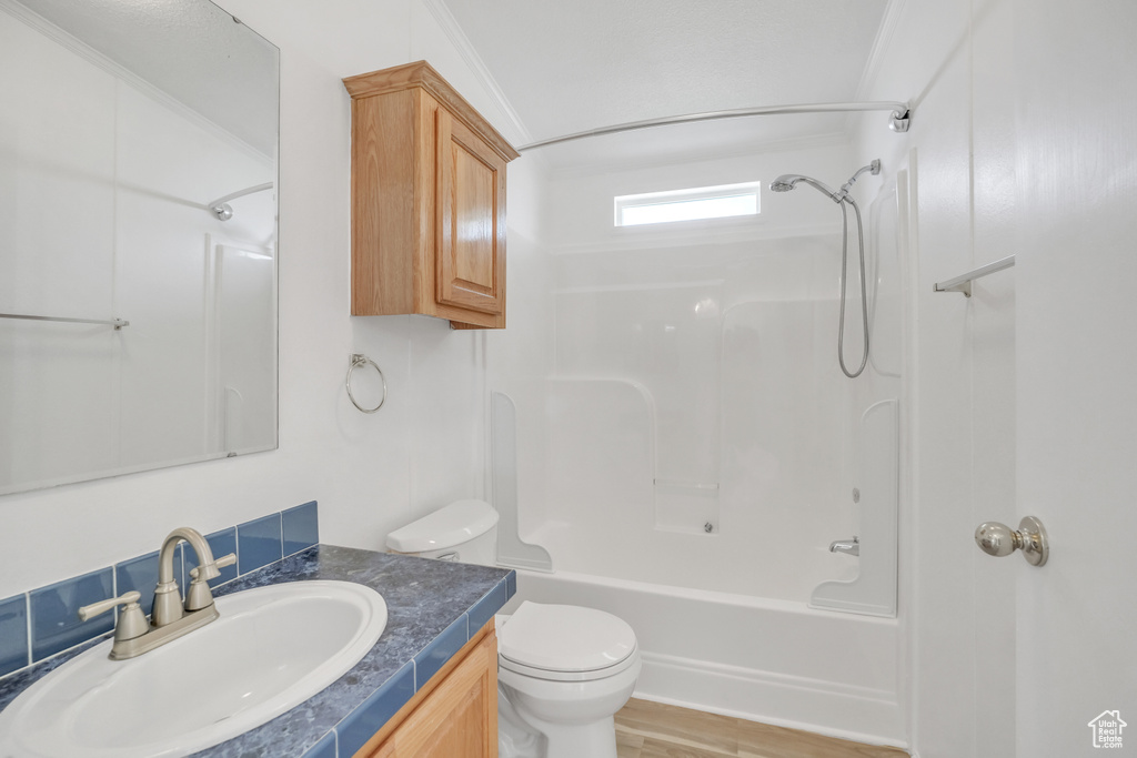 Full bathroom with ornamental molding, hardwood / wood-style flooring, shower / washtub combination, vanity, and toilet