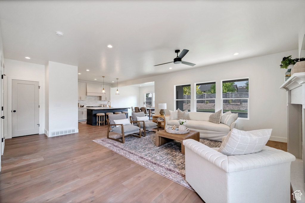 Living room featuring ceiling fan, sink, light hardwood / wood-style flooring, and a fireplace