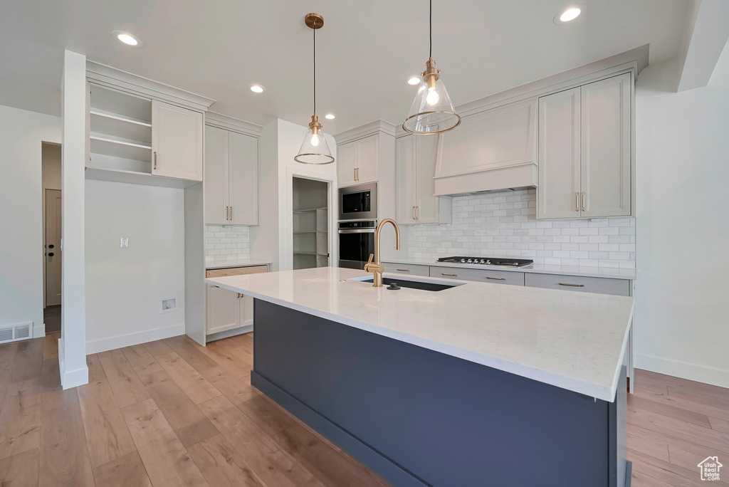 Kitchen with an island with sink, tasteful backsplash, and appliances with stainless steel finishes