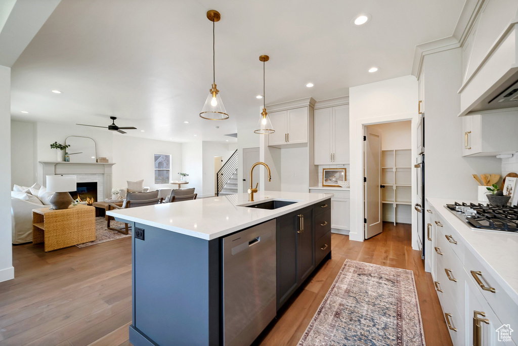 Kitchen with a center island with sink, stainless steel appliances, light hardwood / wood-style flooring, and sink