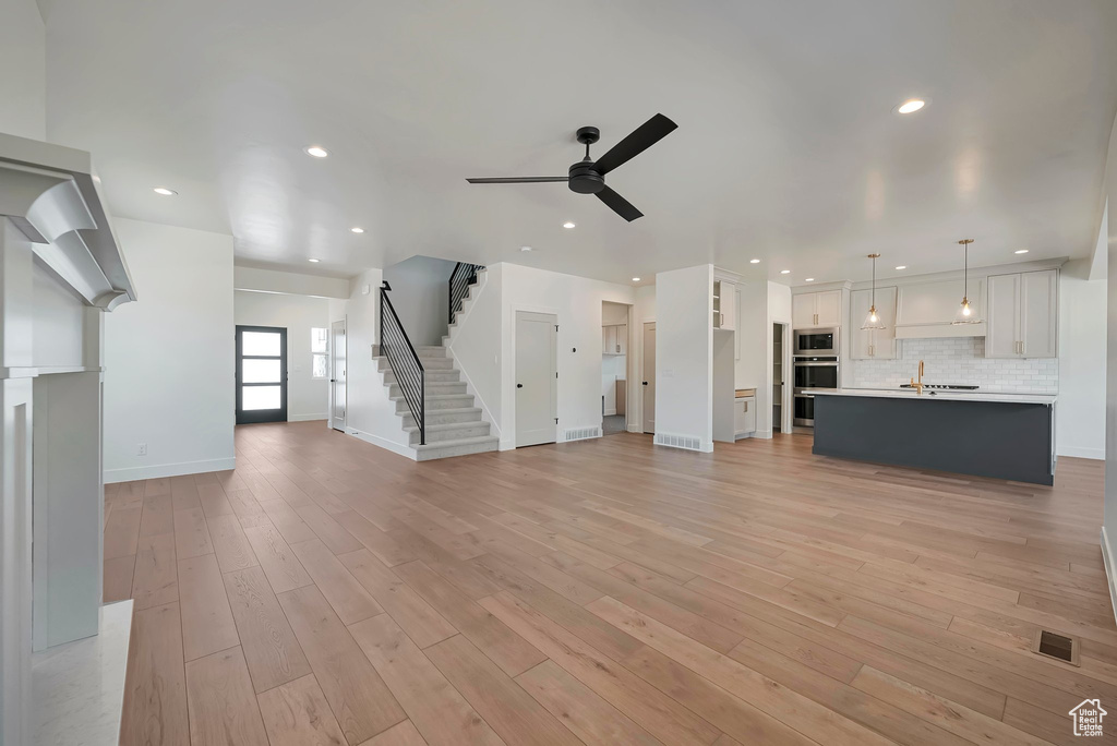 Unfurnished living room featuring ceiling fan, sink, and light hardwood / wood-style floors