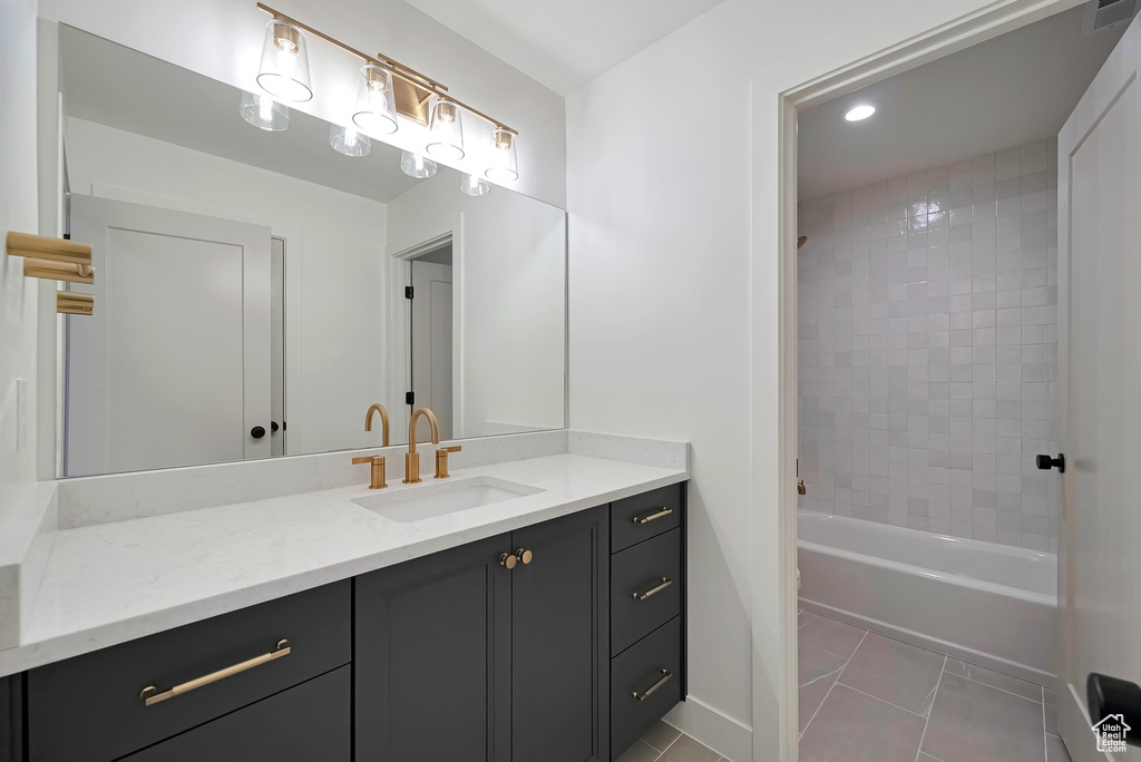 Bathroom featuring tiled shower / bath, tile flooring, and vanity